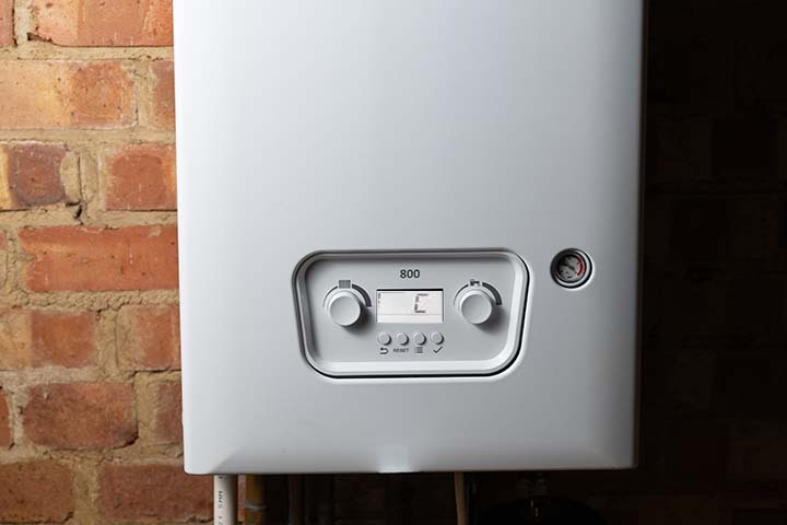 Ideal boiler showing Status C on display, with technician checking for fault and fixing heating issue