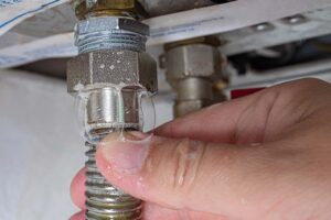 Leaking boiler with water drips, showing signs of damage and urgency for emergency repair in a UK home.