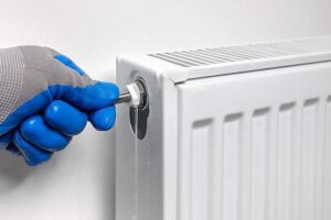 Person bleeding a radiator using a bleed key near valve