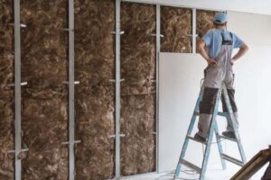 Man installing internal wall insulation to stop heat loss in a UK home