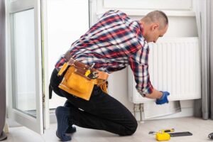 Person replacing a home radiator with tools on the floor in a UK living room